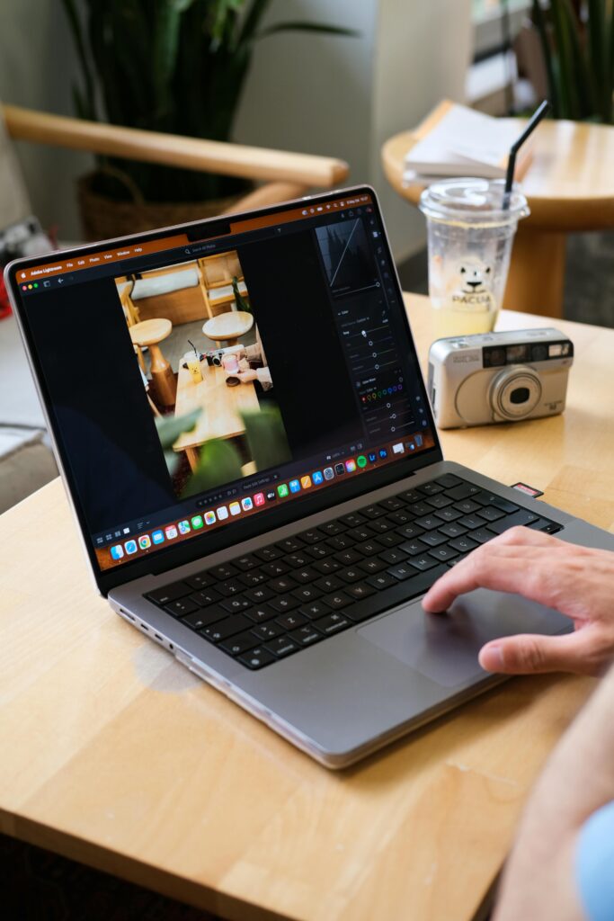 Person edits photo on laptop in a cozy café, capturing creative digital work vibe. Freelancing in Video Editing